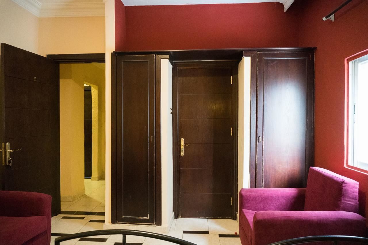 Een hotel lobby met een rode wand, een houten deur en een rode bank.