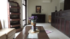 A living room with a wooden coffee table, a vase with flowers, a sofa, and a fireplace. - Madaba Hotel (Madaba)