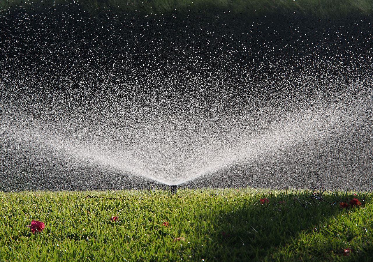 A sprinkler system in a grassy field.