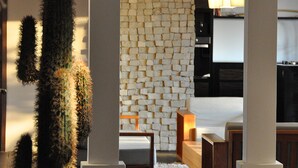 Um interior moderno com parede de pedra, móveis de madeira e uma planta cacto.