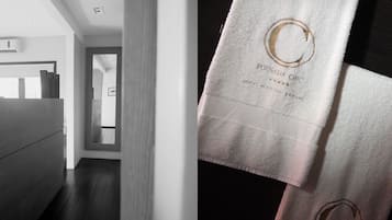 A modern hotel room with a wooden floor, a large mirror, and a white bed.