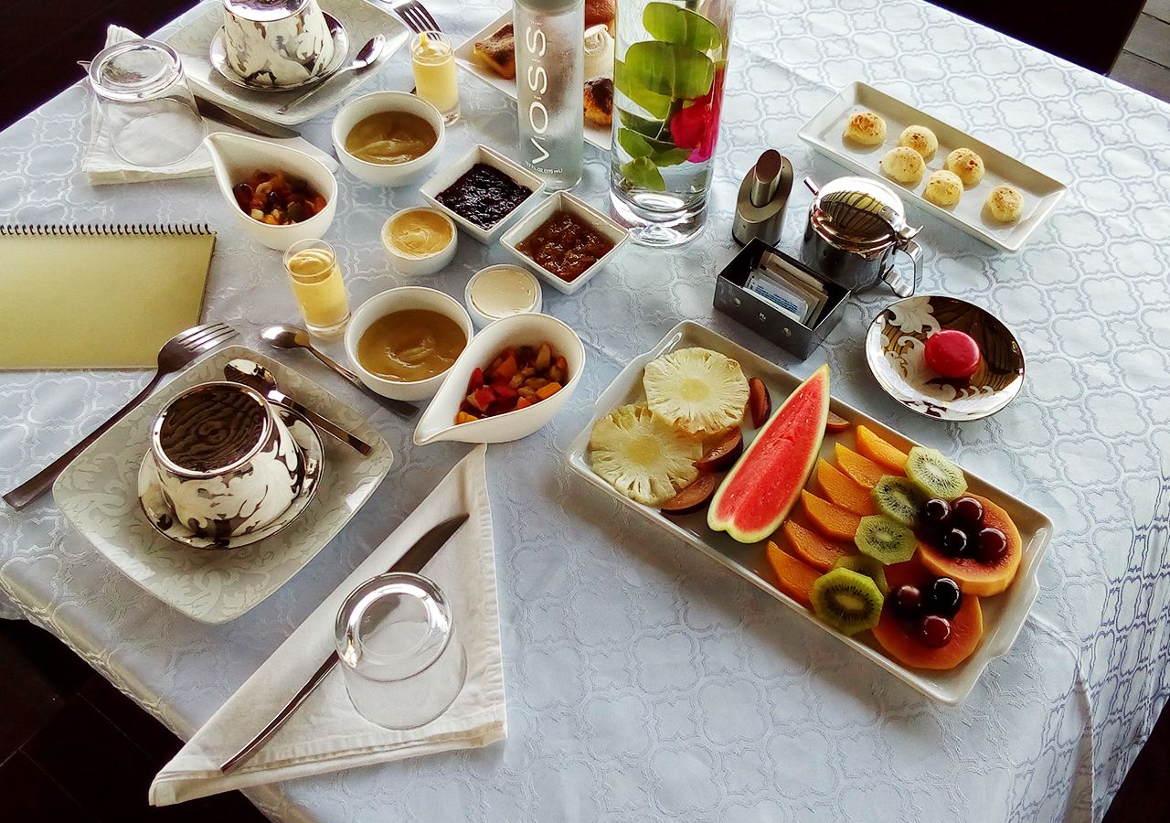 Una mesa servida con diferentes platos, incluyendo un postre, fruta y salsas.