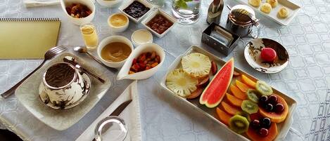 Una mesa servida con diferentes platos, incluyendo un postre, fruta y salsas.