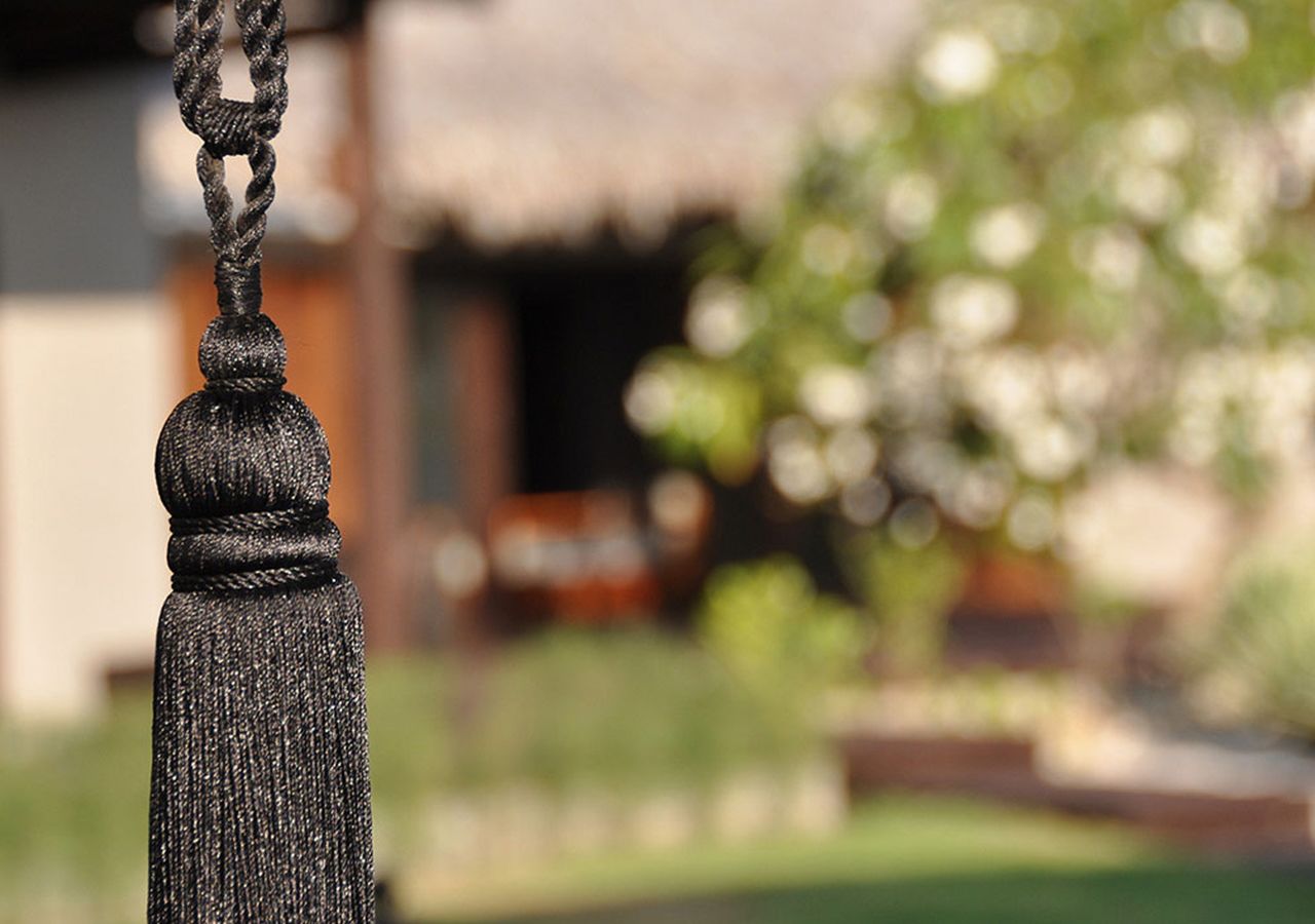 A close-up of a textured, dark-colored tassel hanging from a chain.