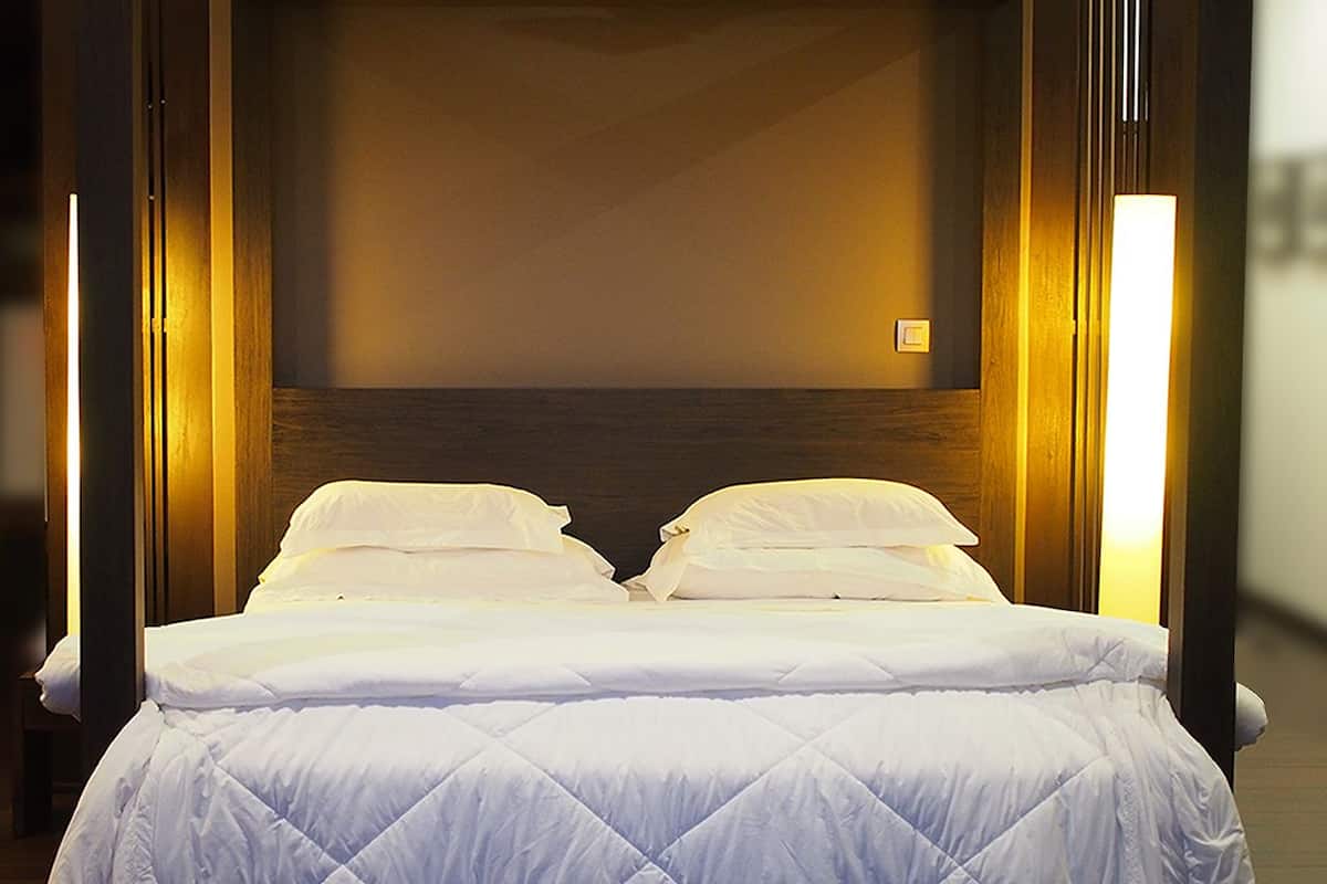 A bed with white bedding and a wooden headboard in a hotel room.