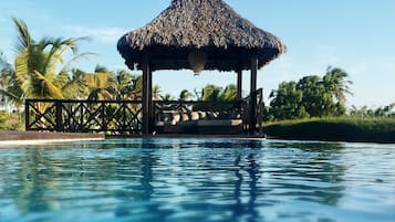 Una piscina al aire libre, sombrillas, sillones reclinables de piscina