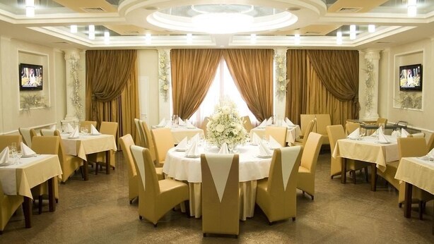 Un comedor formal con mesas redondas, sillas color beige y un arreglo floral central.