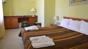 Una habitación de hotel con una cama, un escritorio, una silla y una mesita.