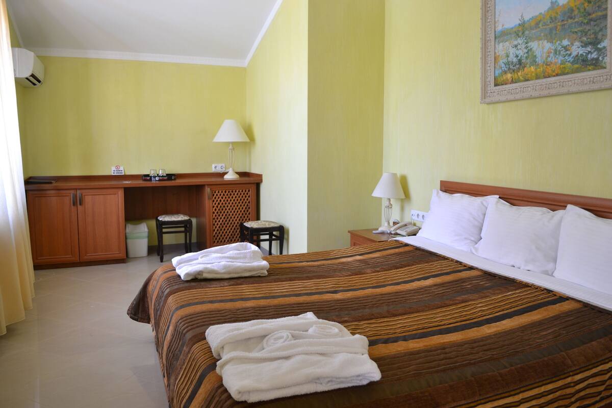 A hotel room with a bed, a desk, a chair, and a small table.