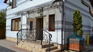 Un edificio de dos pisos con base de piedra y revestimiento blanco.