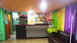 Una habitación con piso de madera, un sofá, una mesita con mantel amarillo y una zona de bar con cabecera capitonada.
