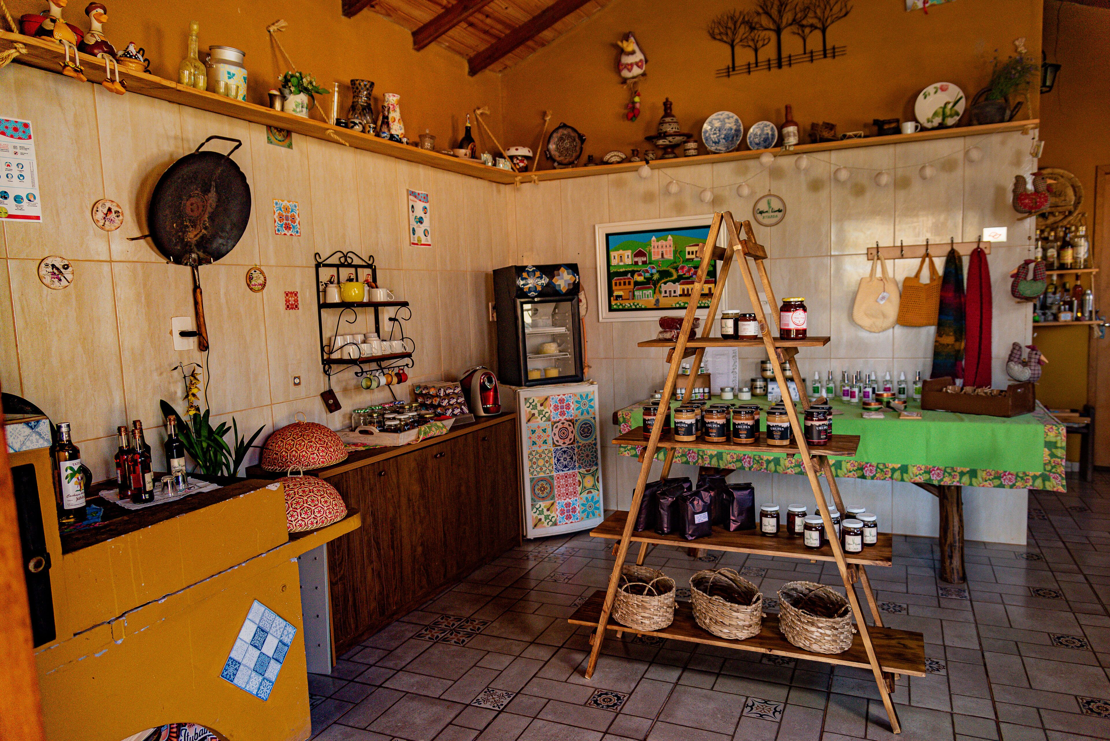 A kitchen with a wooden counter, shelves with jars, a refrigerator, and a ladder shelf.