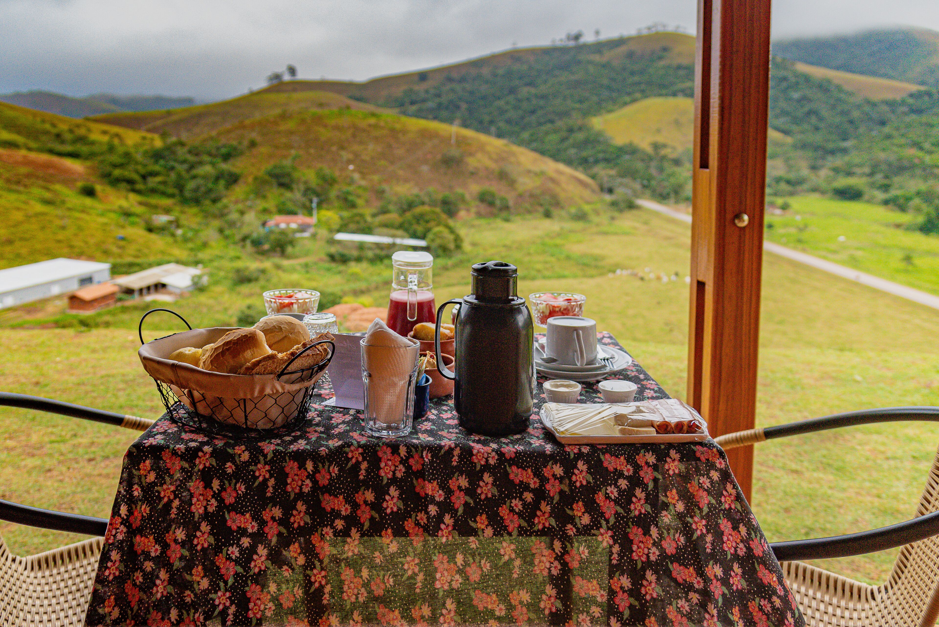 Une table dressée avec des aliments pour le petit-déjeuner, offrant une vue sur des collines verdoyantes.
