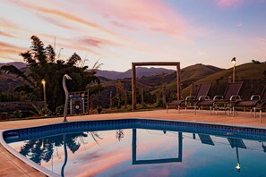 Una piscina al aire libre, sombrillas, sillones reclinables de piscina
