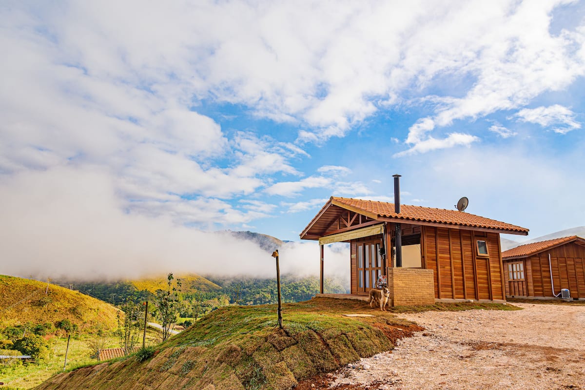 A wooden cabin with a tiled roof, a satellite dish, and a dog nearby.