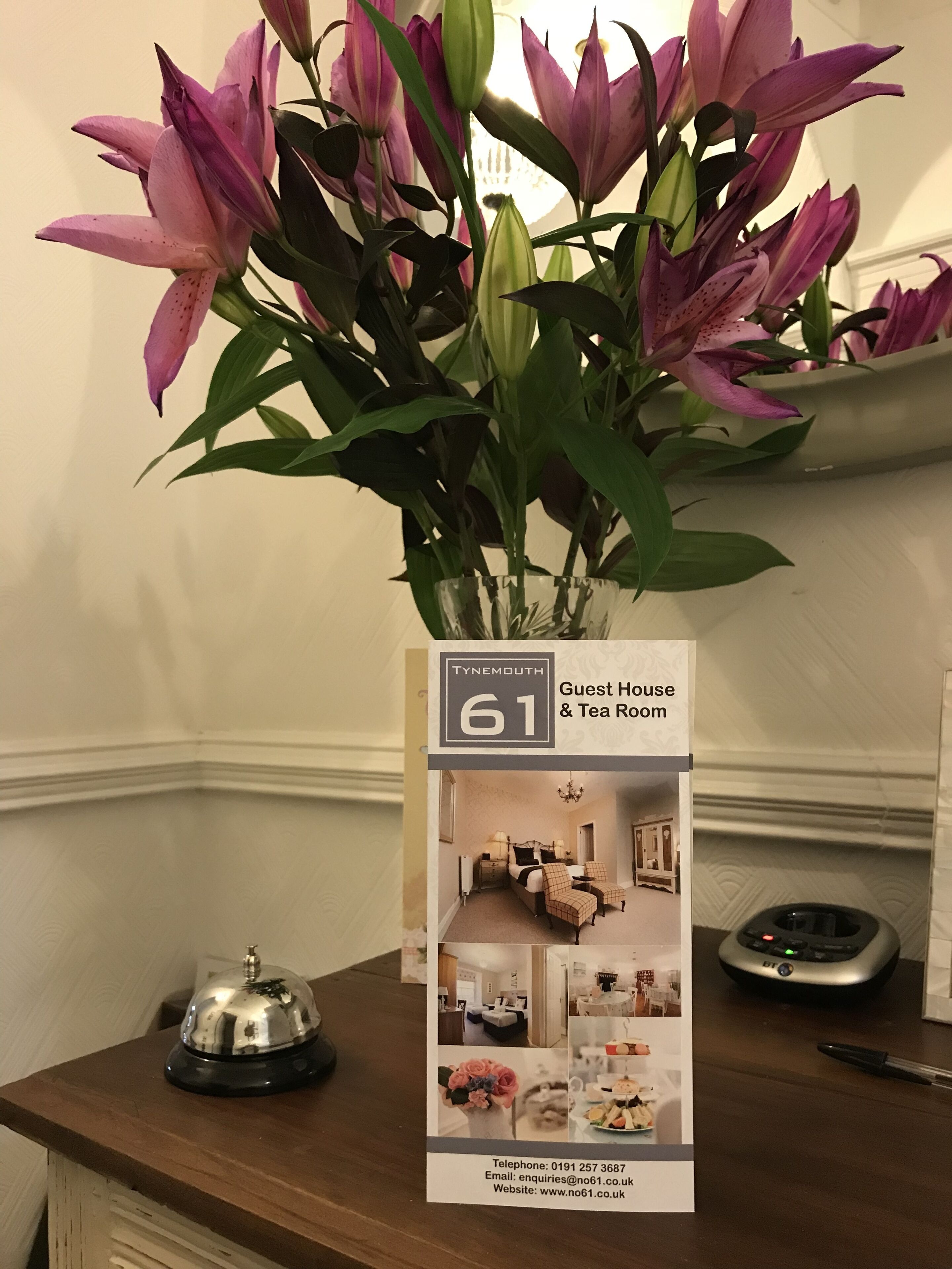 En brochure for et pensionat og tehus med en blomsteropsætning på et bord.