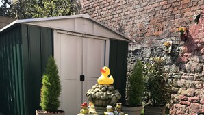 A stone fountain with a lion head, surrounded by potted plants and a brick wall. - Number 61 Guest House and Tea Room (North Shields)