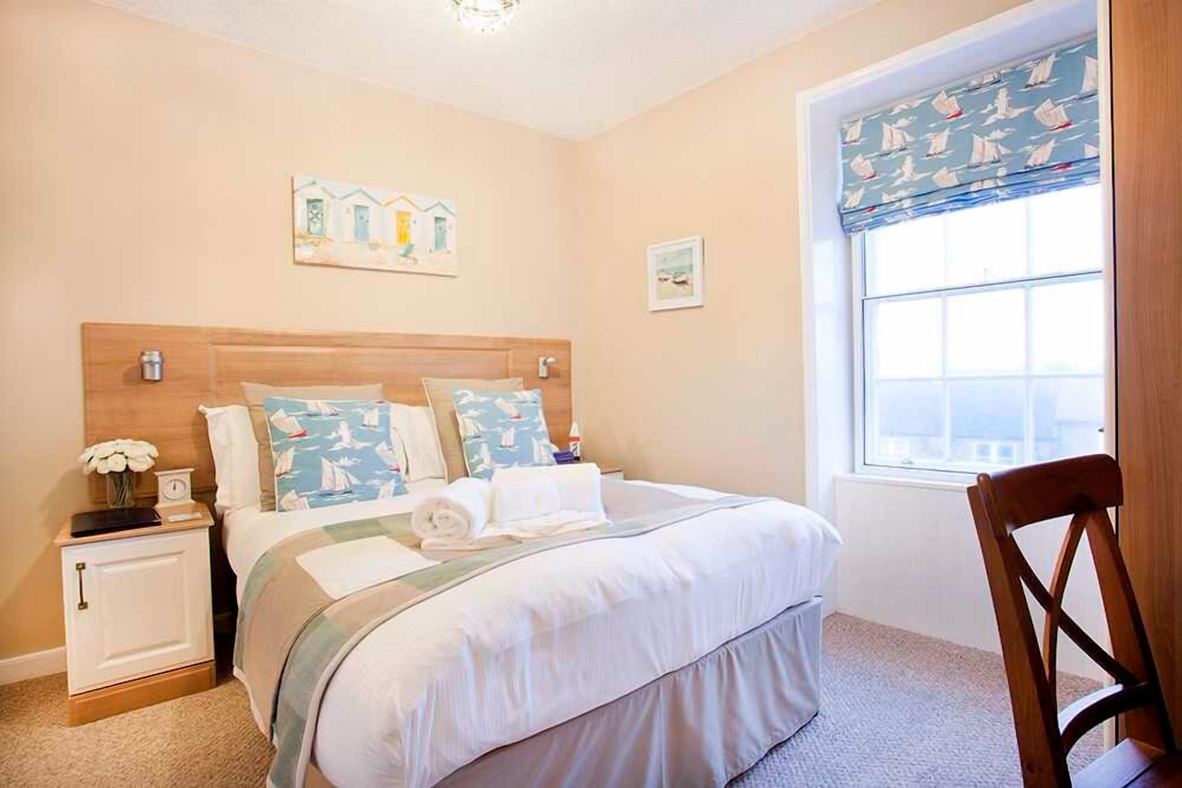 A bedroom with a bed, bedside tables, a window with a view, and artwork on the walls.