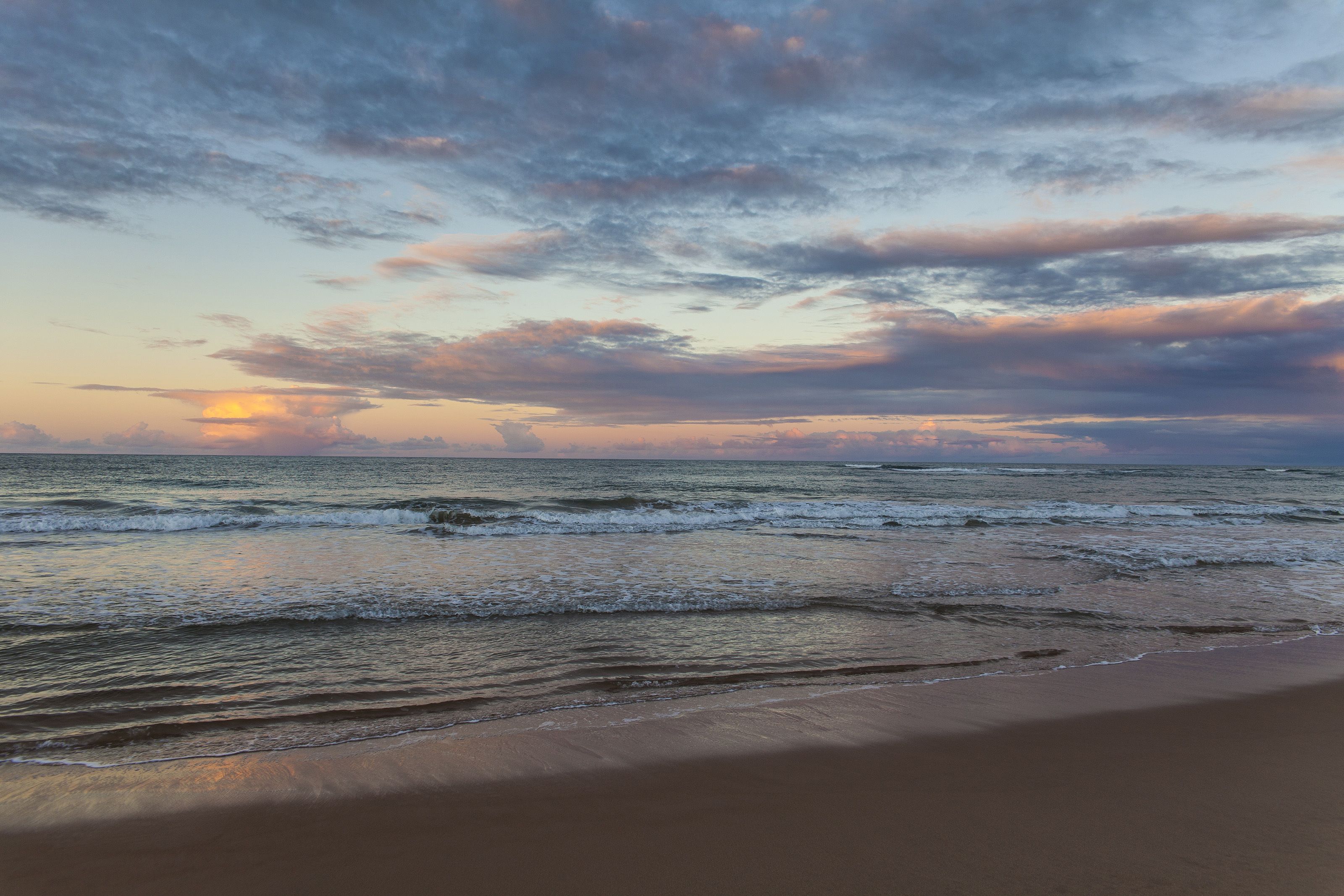 Une plage avec des vagues et un coucher de soleil.