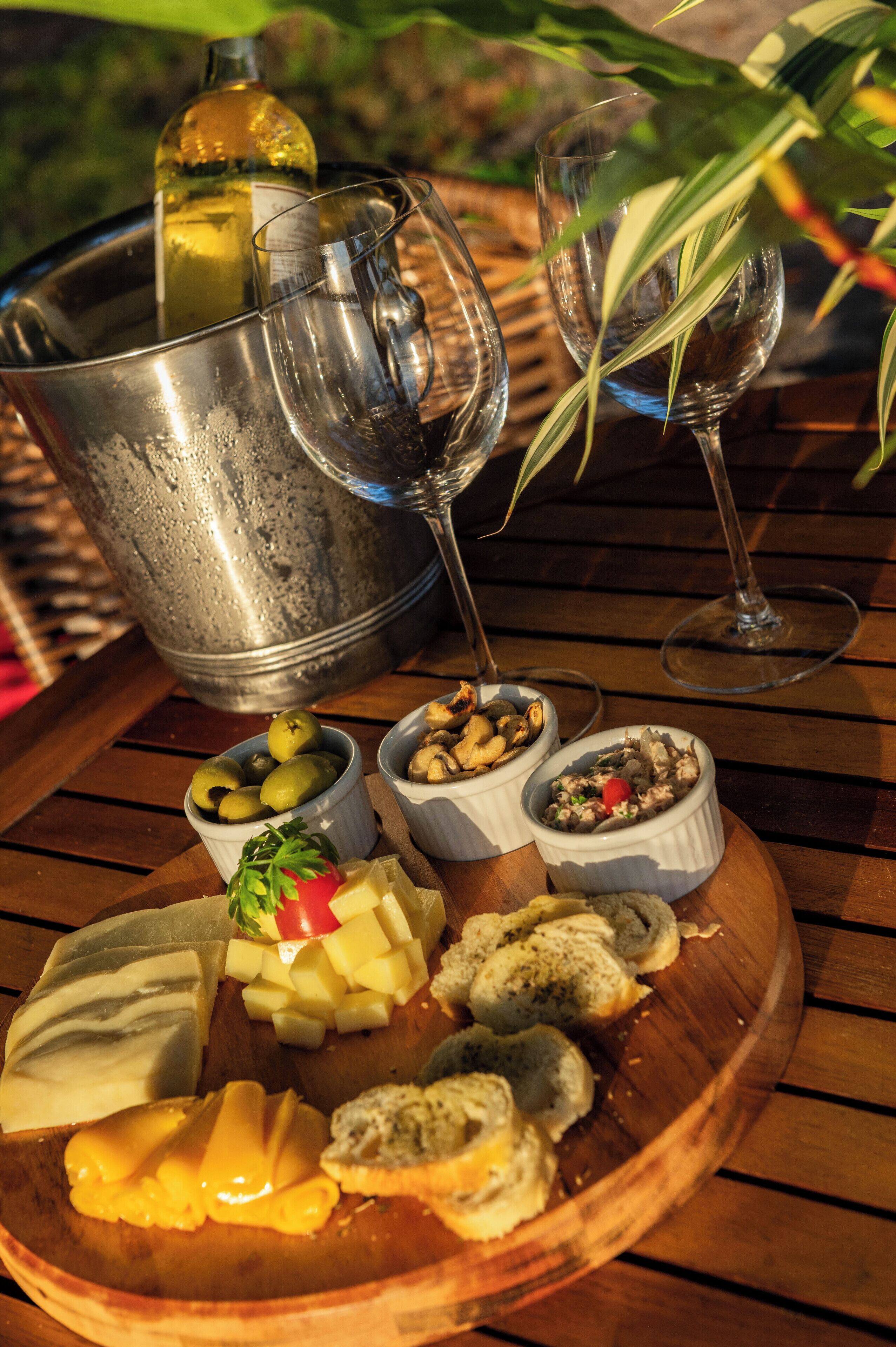 A wooden table with a variety of food items and two wine glasses.