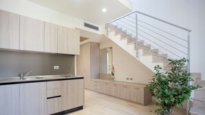 A modern kitchen with wooden cabinets, a built-in sink, and a staircase leading to an upper level.