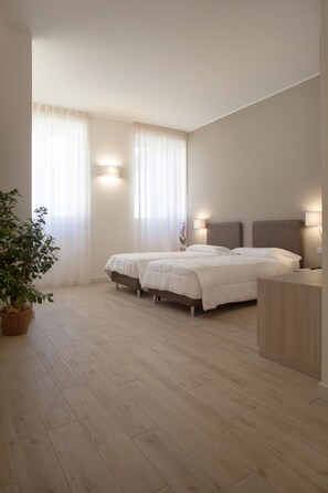 A modern bedroom with a large bed, two bedside lamps, and a potted plant. - Residence Le Querce Monza (Monza)