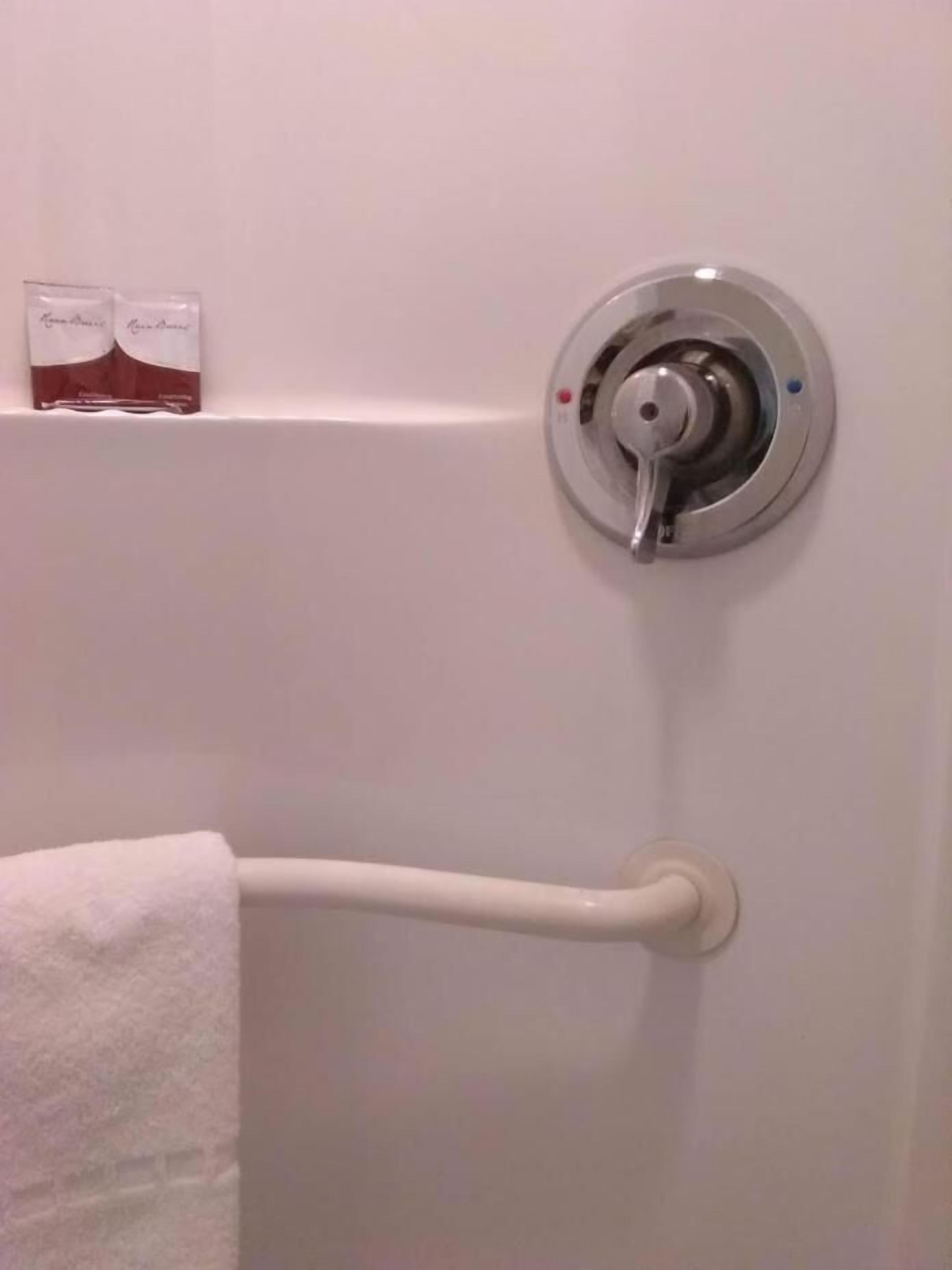 A bathroom with a white towel rack, a silver faucet, and a pair of toiletries on the wall.