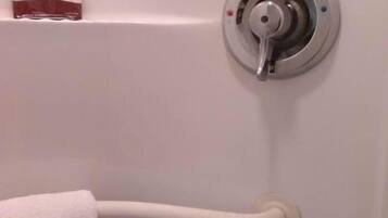 A bathroom with a white towel rack, a silver faucet, and a pair of toiletries on the wall.