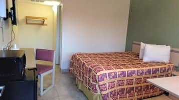 A small hotel room with a bed, a desk, and a chair.