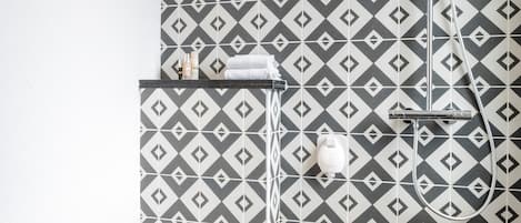 A bathroom with a patterned tile wall, a toilet, and a shower.