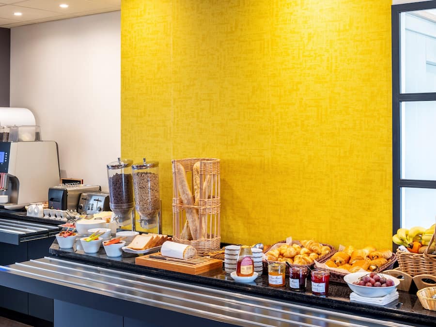 A breakfast buffet with various food items, a coffee machine, and a juice dispenser.