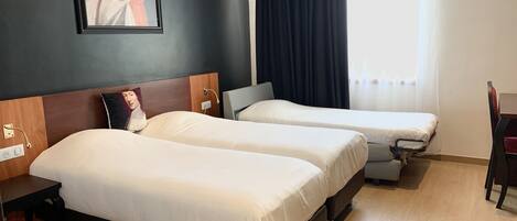 Una habitación de hotel con dos camas individuales, un escritorio y una silla.