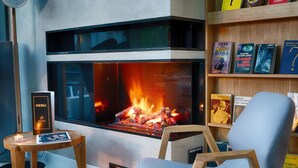 A modern living room with a fireplace, a bookshelf, and a comfortable chair.
