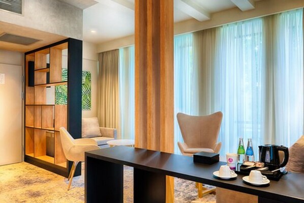 Een moderne hotelkamer met een groot raam, een houten boekenkast, een bank, een bijzettafeltje en een ontbijtje.