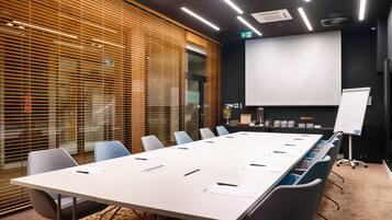 Une salle de conférence équipée d’une longue table, de chaises, d’un écran de projection et d’un tableau blanc.