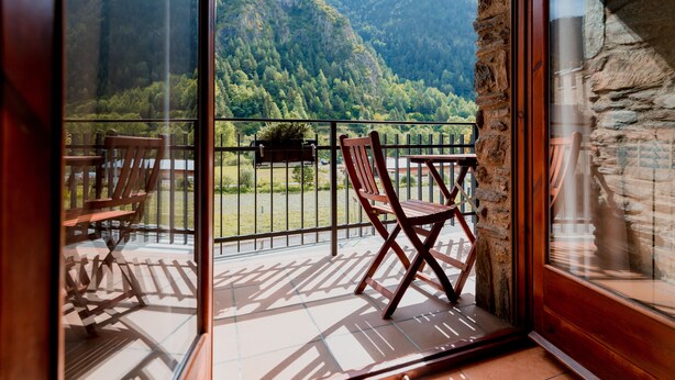 Un balcon avec vue sur une montagne boisée.