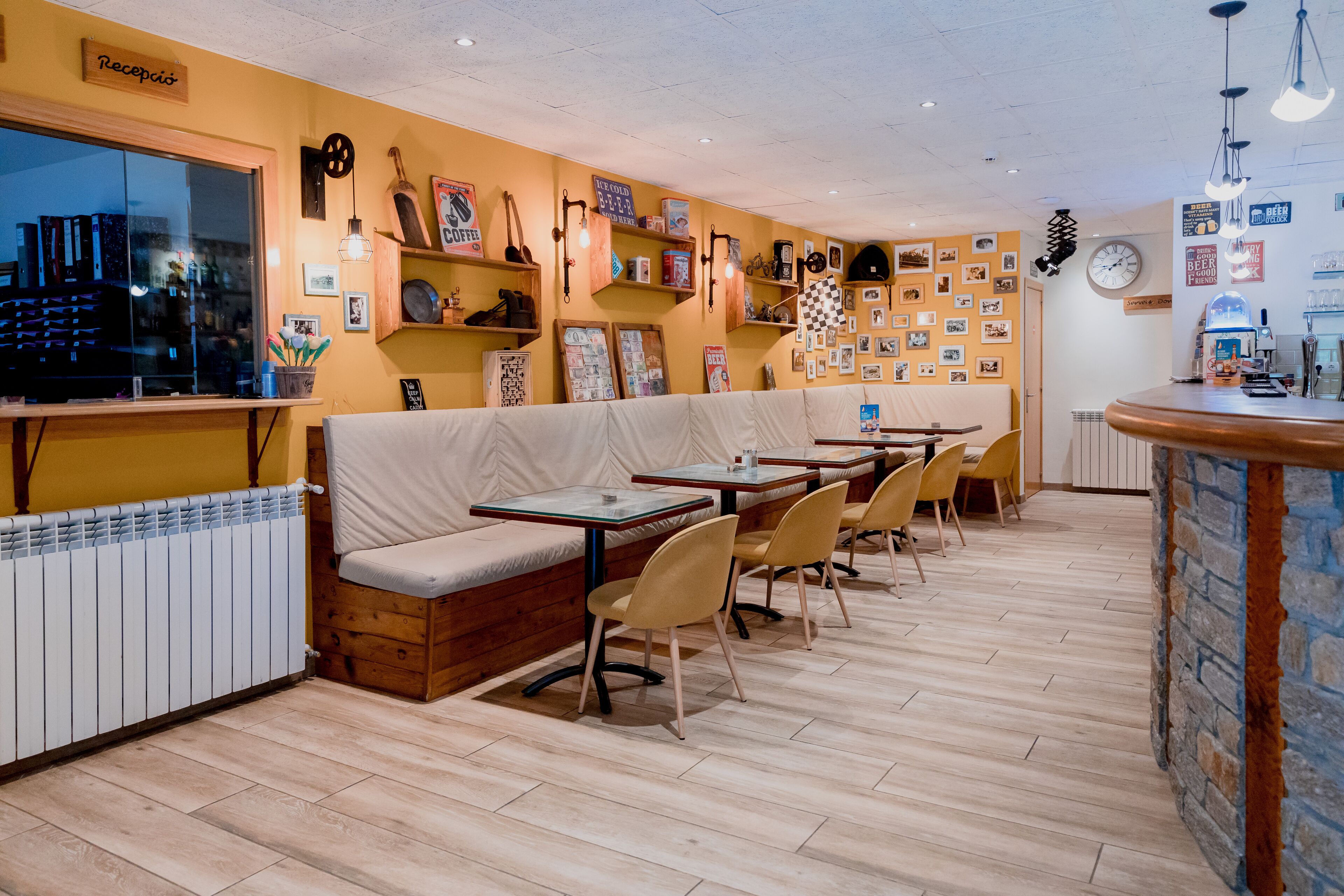 A cozy restaurant with wooden furniture, a bar area, and a wall decorated with photos and signs.