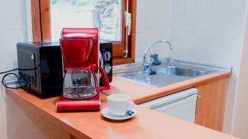 A kitchen with a coffee maker, a cup of coffee, and a sink.