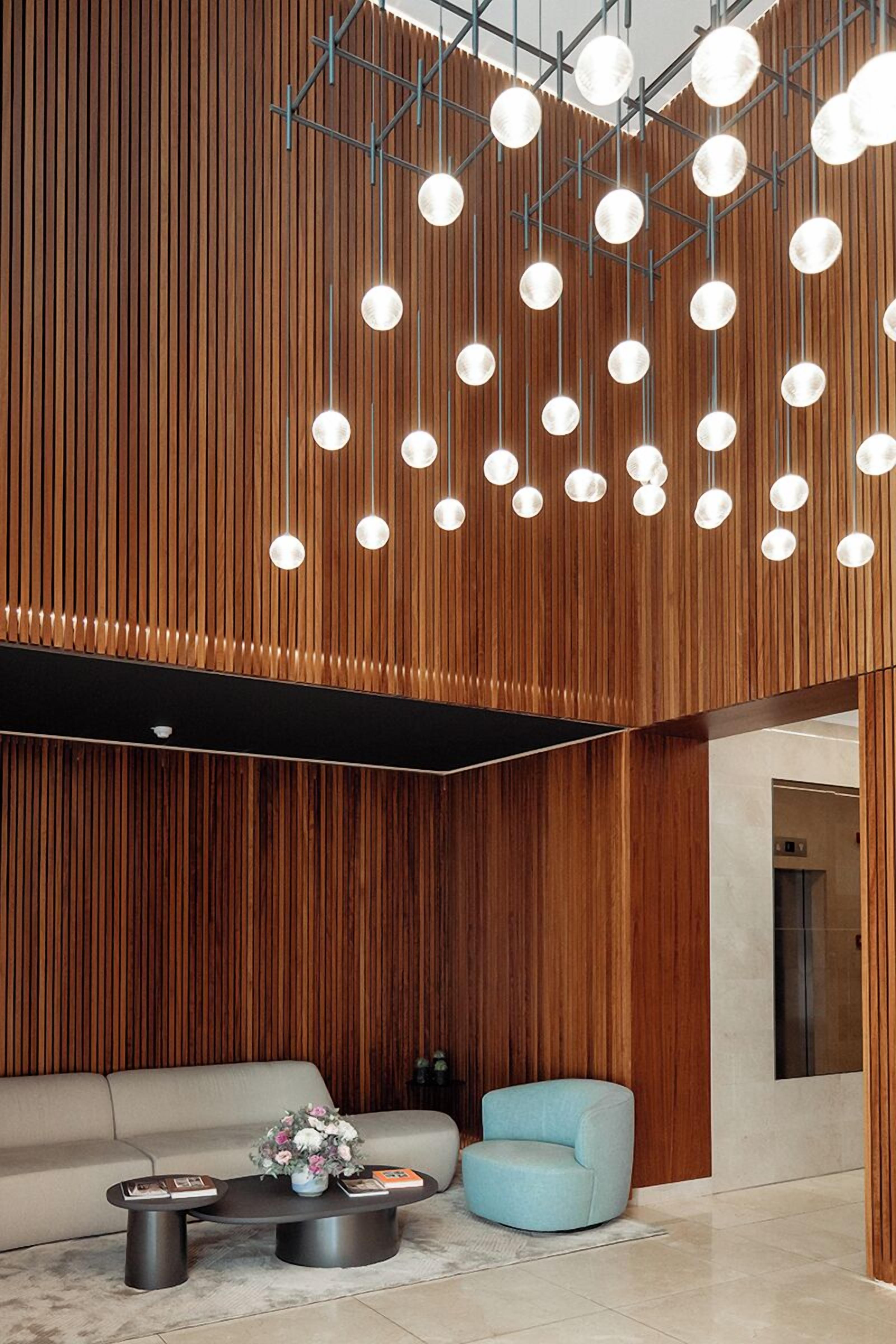 Un interior moderno con un panel de madera, un sofá, un sillón azul y una mesa de centro con libros y flores.