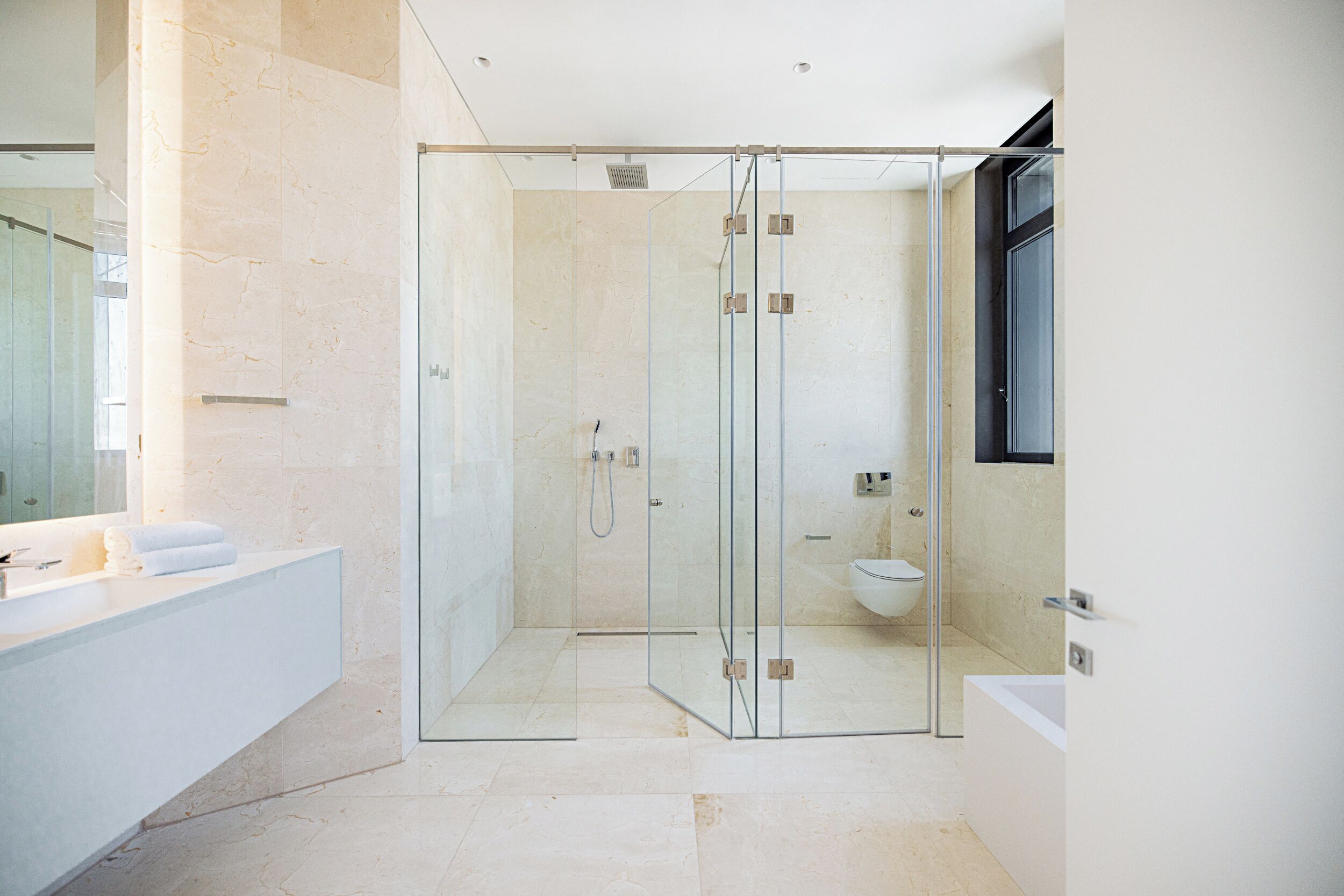 A modern bathroom with a glass-enclosed shower, a white bathtub, and a large mirror.