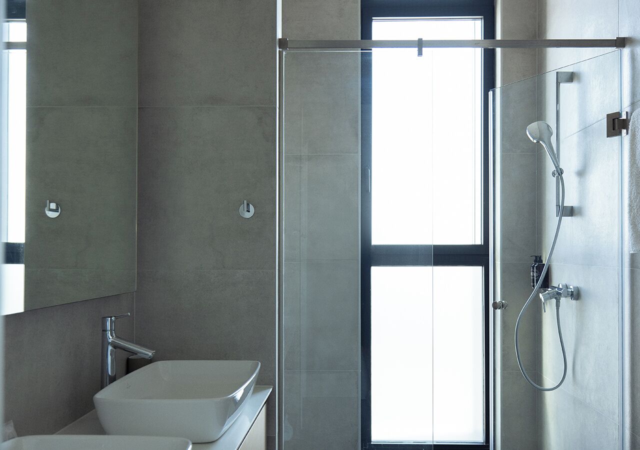 A modern bathroom with a glass shower enclosure, a white sink, and a large mirror.