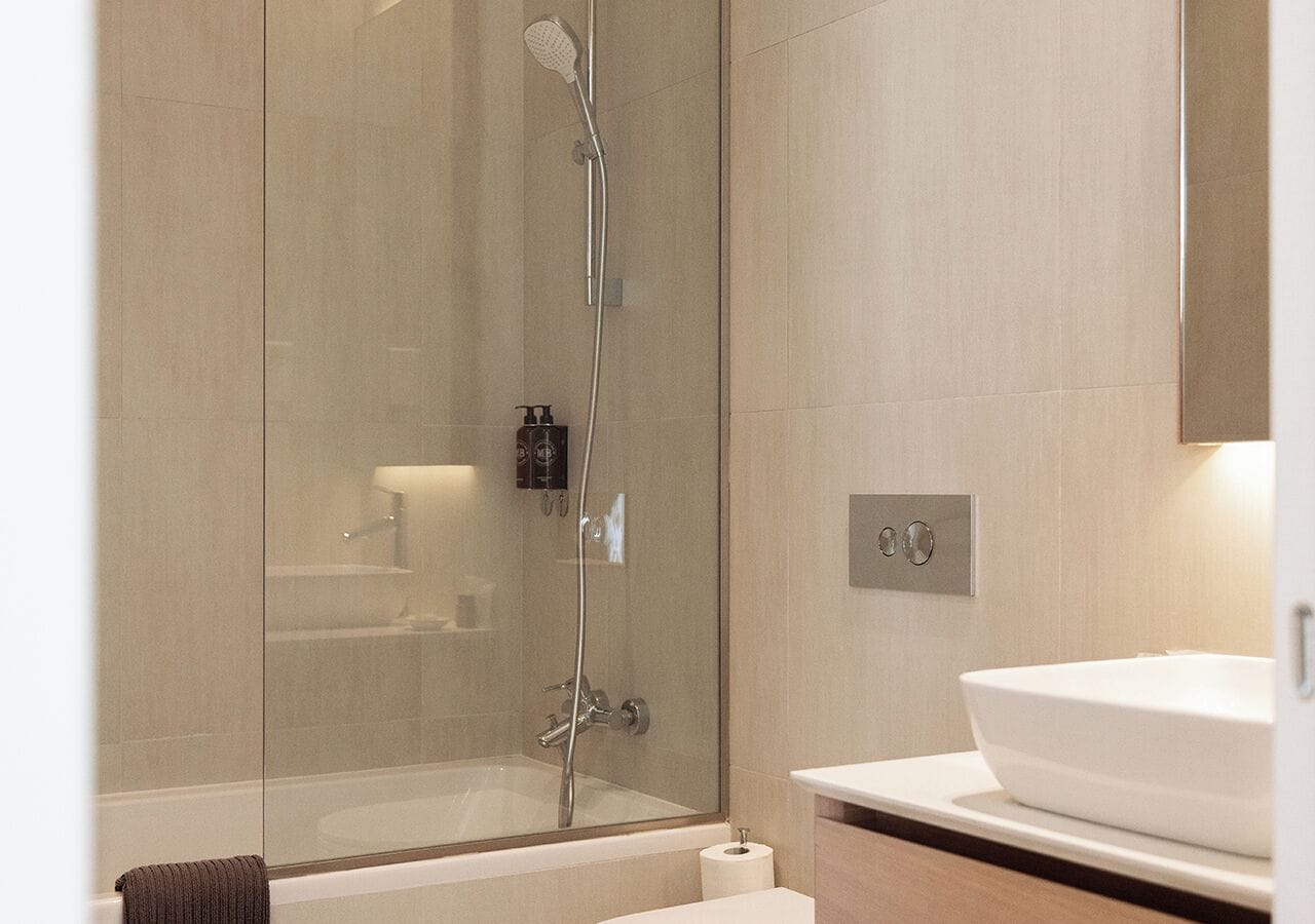 Un baño moderno con cabina de ducha de vidrio, un lavabo blanco y un espejo sobre el lavabo.