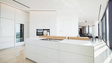 A modern kitchen with white cabinetry, a central island, and a built-in oven.