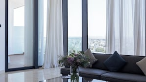 Una sala de estar moderna con un ventanal grande, un sofá y un jarrón de flores.