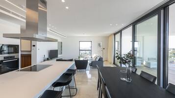 A modern kitchen with a central island, bar stools, and a dining area with a table and chairs.