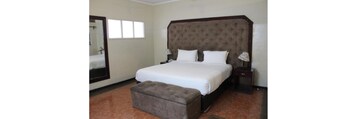 Un dormitorio con una cama grande, una mesita de noche, una lámpara, un espejo y una ventana.