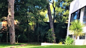 A well-maintained grassy area with a modern building in the background. - Engy Estoril - Luxury Villas (Cascais)