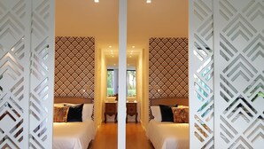 A mirrored room with a geometric patterned wall, a bed with white bedding, a nightstand, and a window with a view of greenery. - Engy Estoril - Luxury Villas (Cascais)
