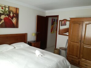 Ein Hotelzimmer mit einem großen Bett, einem Holzschrank, einem Gemälde an der Wand und einem kleinen Tisch mit einer Lampe.