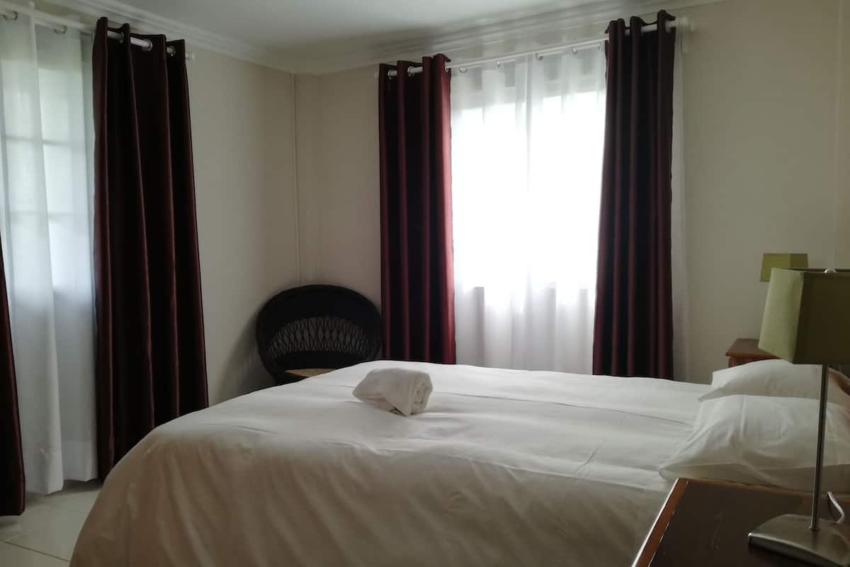 Una habitación de hotel con una cama grande, una silla, una mesita de noche y una lámpara.